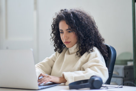 Young business woman worker sitting at office desk working on laptop.