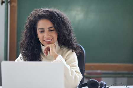 Young woman school teacher, online tutor sitting at desk teaching remote class.