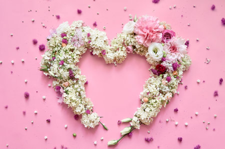 Flowers petals heart on pink floral pastel background. Flat lay, top viewの写真素材