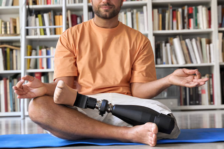 Amputee man with prosthetic leg prosthesis meditating doing yoga at home.の写真素材