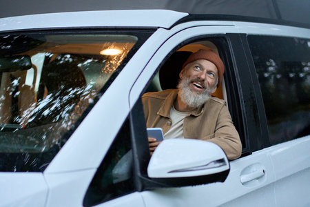 Excited happy older man driving rv camper van looking outside enjoying view.