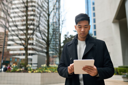 Young Asian business man professional standing in city using digital tablet.