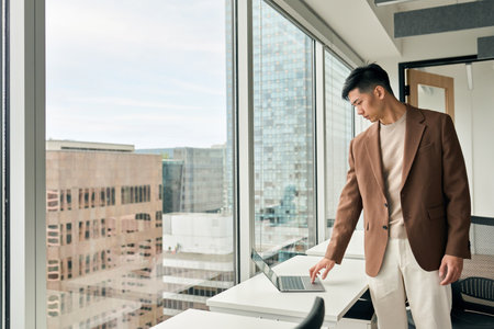 Young busy Asian business man worker using laptop standing in office.