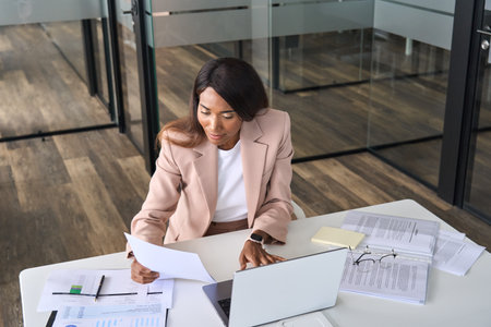 Busy business woman executive holding document using laptop in office.の写真素材