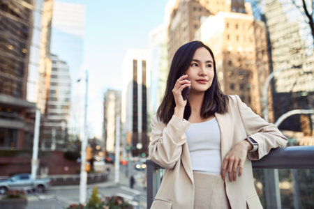 Young pretty Asian business woman standing on city street making phone call.の写真素材