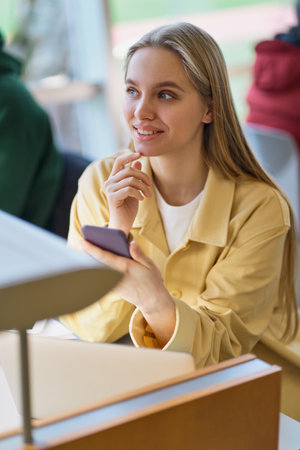 Teenage girl gen z student using cell phone looking away. Verticalの写真素材