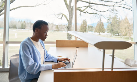 Busy African girl student using laptop computer sitting in university campus.