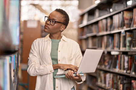 African Black girl student using laptop standing in college library.の写真素材