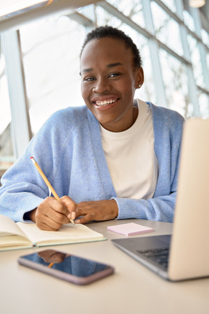 Happy African girl student using laptop learning online. Vertical portrait