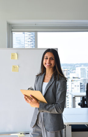 Happy professional Indian business woman standing in office, portrait.の写真素材