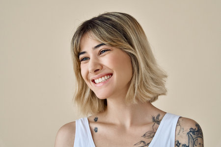 Smiling happy blonde gen z girl pretty face looking away at beige background.の写真素材