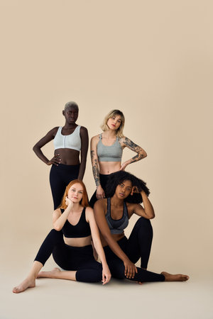 Fit healthy cool diverse girls wearing sportswear posing at beige background.の写真素材
