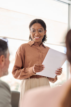Smiling young African American businesswoman communicating at group meeting.