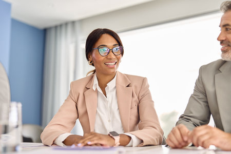 African American business woman wearing suit glasses talking at meeting table.の写真素材