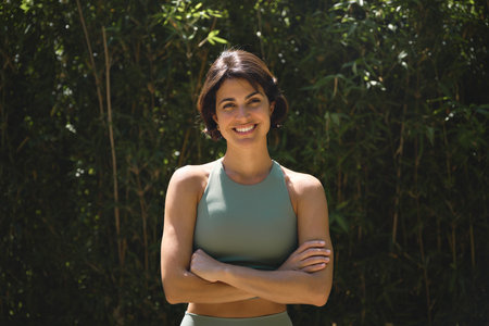 Happy young Hispanic woman looking at camera standing in nature park. Portrait.