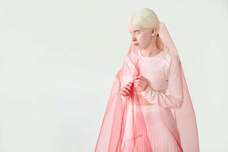 Inclusive beautiful albino woman wearing red veil on white background.