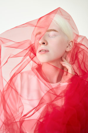 Inclusive beautiful albino woman wearing red veil on white background.の写真素材