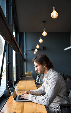 Busy young business man looking at laptop using computer at work. Vertical