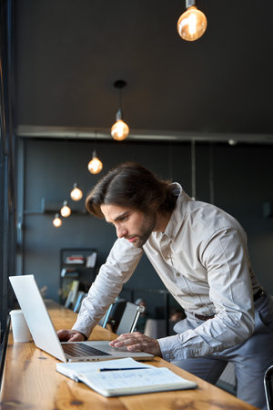 Busy young European business man looking at laptop computer working in office.の写真素材