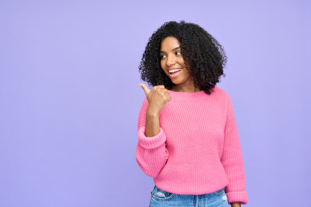 Happy young African American woman pointing isolated on purple background.の写真素材
