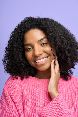 Young smiling woman wearing pink sweater isolated on purple, vertical portrait.