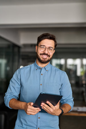 Smiling busy young business man manager using tablet standing in office.の写真素材