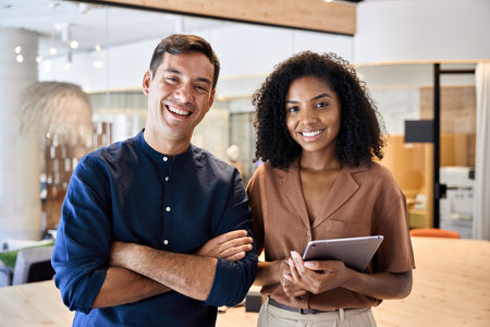 Two young diverse business man and woman team standing in office, portrait.の写真素材