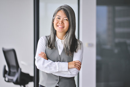 Mature Asian business woman standing in office looking at camera, portrait.の写真素材