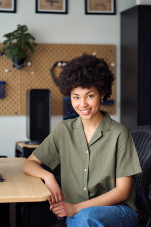 Young happy African girl student sitting at home desk, vertical portrait.
