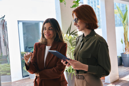 Two happy business women discussing working together in office.