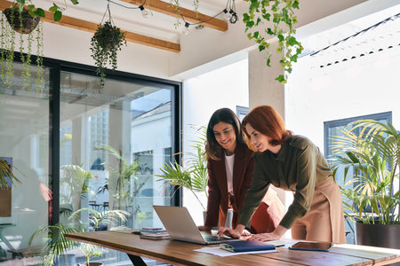 Two happy professional female partners working in office looking at laptop.の写真素材