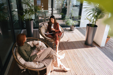 Two busy business women talking working in green sunny office. Top view.の写真素材