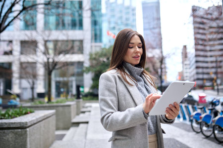 Young busy business woman standing in city using digital tablet.の写真素材