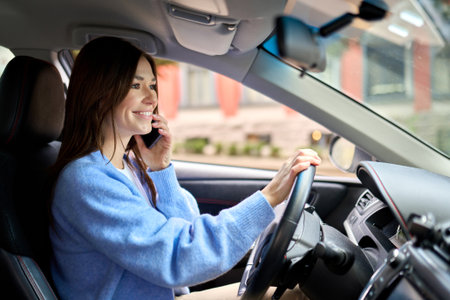 Young happy woman driver driving a car talking on the phone.