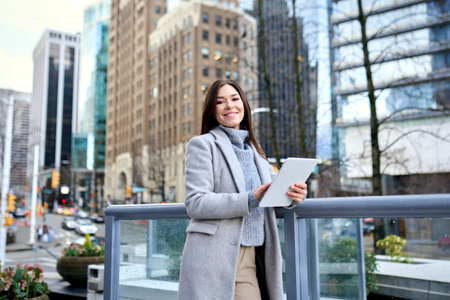 Young happy business woman standing in city using digital tablet.の写真素材