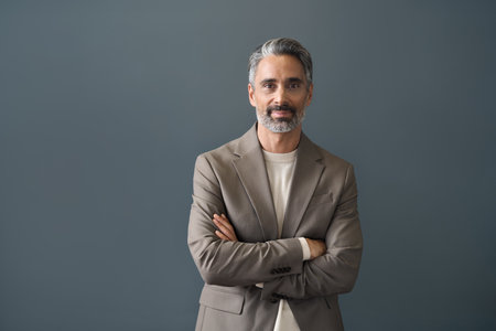 Happy middle aged business man looking at camera standing at gray background.の写真素材