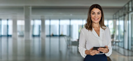 Happy mature business woman executive holding tablet in office. Portrait.の写真素材