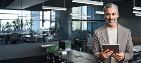 Happy mature business man ceo executive standing in office with tablet.の写真素材