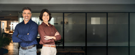 Two happy executives business man and woman standing arms crossed in office.の写真素材