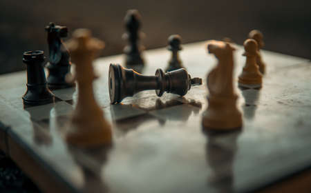 Chess game on the chessboard with selective focus on the matte black king under a sunsetの写真素材