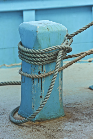 Blue fishing boat, tied to land by a ropeの写真素材
