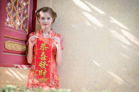 Asian woman in chinese dress holding couplet 'Lucrative' Chinese word with chinese temple...