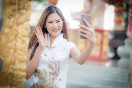 Asian Chinese woman in Traditional Chinese and hold telephone,by background ambience China .の写真素材