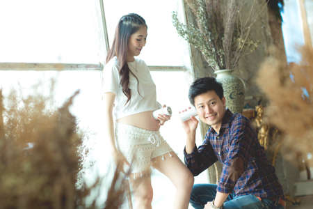 young man and woman with Pregnant Belly talking through a tin phone.