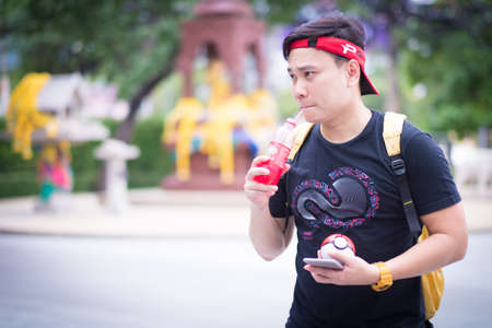 BANGKOK, THAILAND -August 14,2016:  Trainer boy playing pokemon , pokemon ball And are wondering why pokemonstop in a drinking water well  ,Lighting with sun flareのeditorial素材