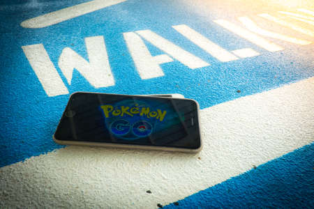 BANGKOK, THAILAND â August 12,2016:iphone user plays Pokemon Go , a free-to-play augmented reality mobile game developed by Niantic for iOS and Android devices. ,Lighting with sun flareのeditorial素材