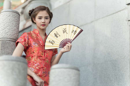 Asian woman in chinese dress holding couplet 'success' (Chinese word) with chinese temple background.の写真素材