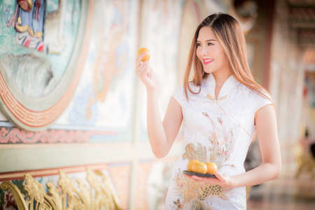 Asian Chinese woman in Traditional Chinese holding orange pay respect,by background ambience China .の写真素材