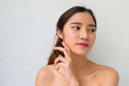 Beautiful young woman with healthy clean skin presenting something on her hand. Isolated on white. asian beautyの写真素材