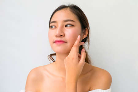 Beautiful young woman with healthy clean skin presenting something on her hand. Isolated on white. asian beautyの写真素材